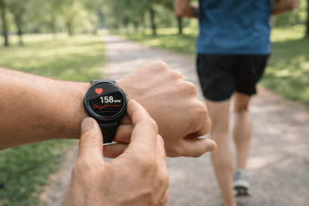 Hyvä syke juoksussa – juoksija tarkistaa sykkeen juoksukellosta